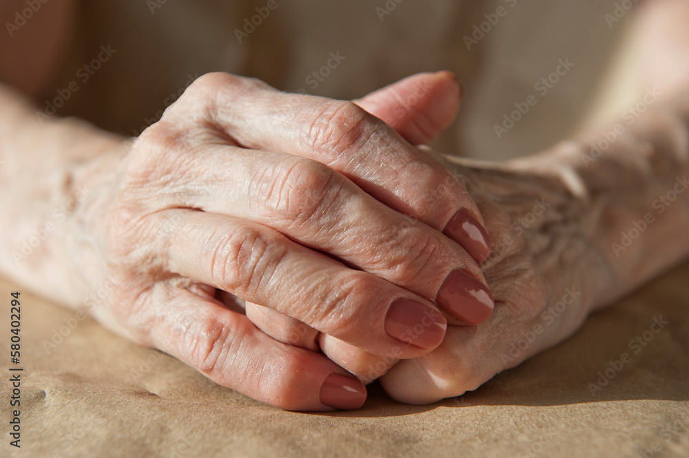 the hands of an elderly woman lie on the table folded one into the other the hands of an elderly woman lie on the table folded one into the other