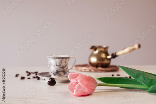 Spring tulip flower, coffee cup on a wooden white table. Pot of coffee, coffee beans 