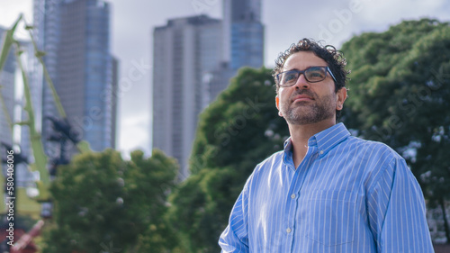 Panoramic photo of a middle aged latin man with inspirational look in the city with blurred background. Copy space.