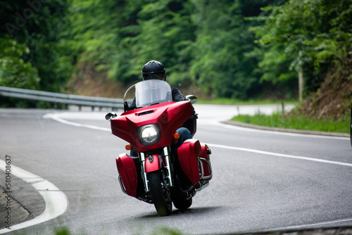Biker on a red cruiser motorcycle riding in the mountains on asphalt road. © Jakub Sisulak