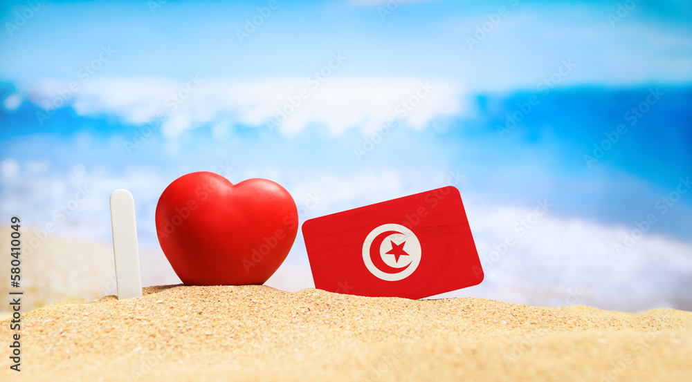 I love Tunisia. Flag of Tunisia on the beach with a red heart. vacation and travel concept. - obrazy, fototapety, plakaty 