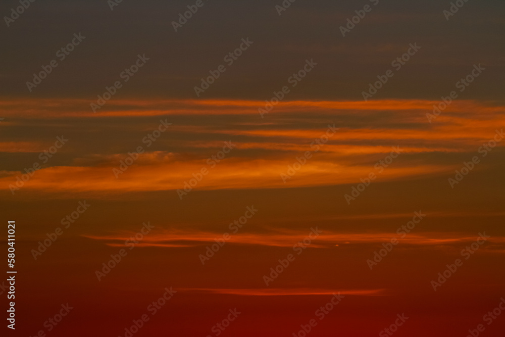 Orange sunset sky with thin cloud lines. Abstract colour tones