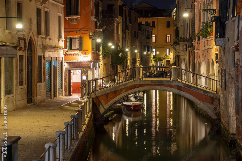 Quiet and calm still life small stone bridge spanning canal by night, Venice, Italy
