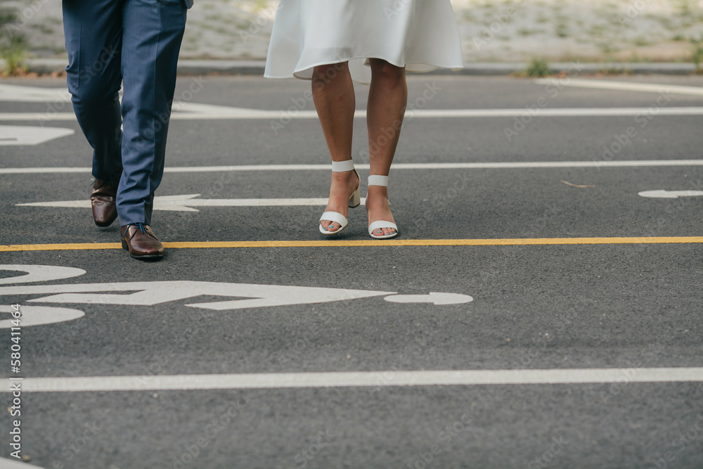 legs of bride in short white dress and sandals and groom in navy blue suit crossing the street in brooklyn