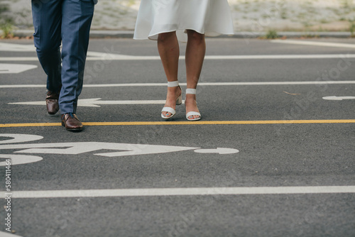legs of bride in short white dress and sandals and groom in navy blue suit crossing the street in brooklyn