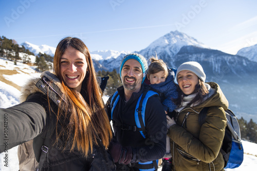 Canvas Print Happy family taking a picture of themselves enjoying a walk in the mountains in winter