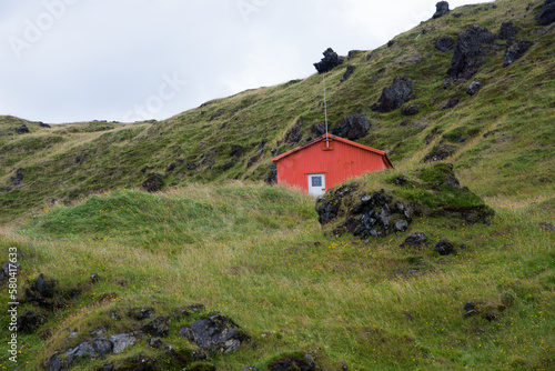 Beautiful landscape with green hill and small wooden hut. Iceland