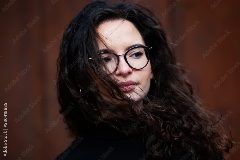 Beautiful young woman with brunette curly hair, portrait in eye glasses enjoying the sun in the city. Beautiful young woman with brunette curly hair, portrait in eye glasses enjoying the sun in the city.