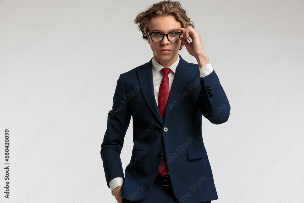 businessman holding a hand in pocket and fixing eyeglasses businessman holding a hand in pocket and fixing eyeglasses