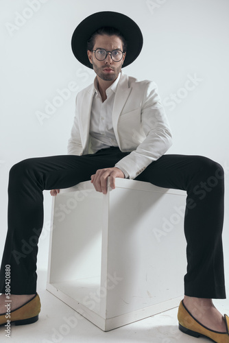 sexy fashion man wearing hat and glasses and posing in a cool way photo