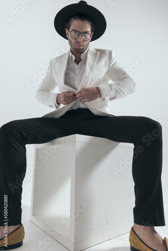 fashion man with hat and glasses unbuttoning white jacket suit photo