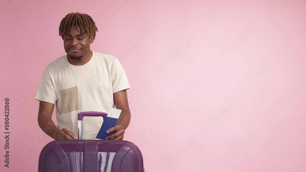 Vacation trip. Flight departure. Advertising background. Happy black man looking copy space posing with suitcase passport and tickets on pink. Vacation trip. Flight departure. Advertising background. Happy black man looking copy space posing with suitcase passport and tickets on pink.