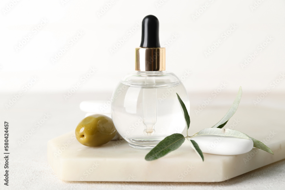 Board with bottle of olive essential oil on light background, closeup Board with bottle of olive essential oil on light background, closeup