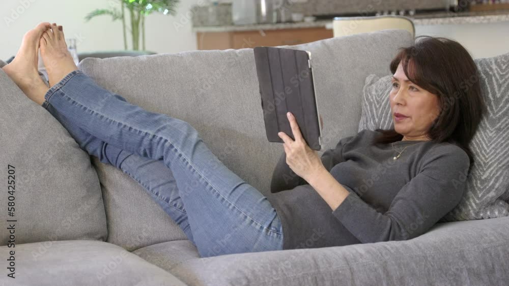 Attractive woman excited laying on sofa shopping online with mobile tablet buying Attractive woman excited laying on sofa shopping online with mobile tablet buying