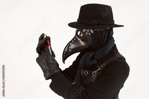 Plague doctor from Medieval era holding a syringe and needle with Medicine or serum, antidote. high-quality costume. Isolated on a white background. COVID-19, epidemic and pandemic concept.