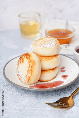 Plate with delicious cottage cheese pancakes on light background, closeup photo