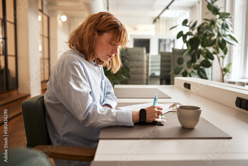 Businesswoman writing in a notebook at work
