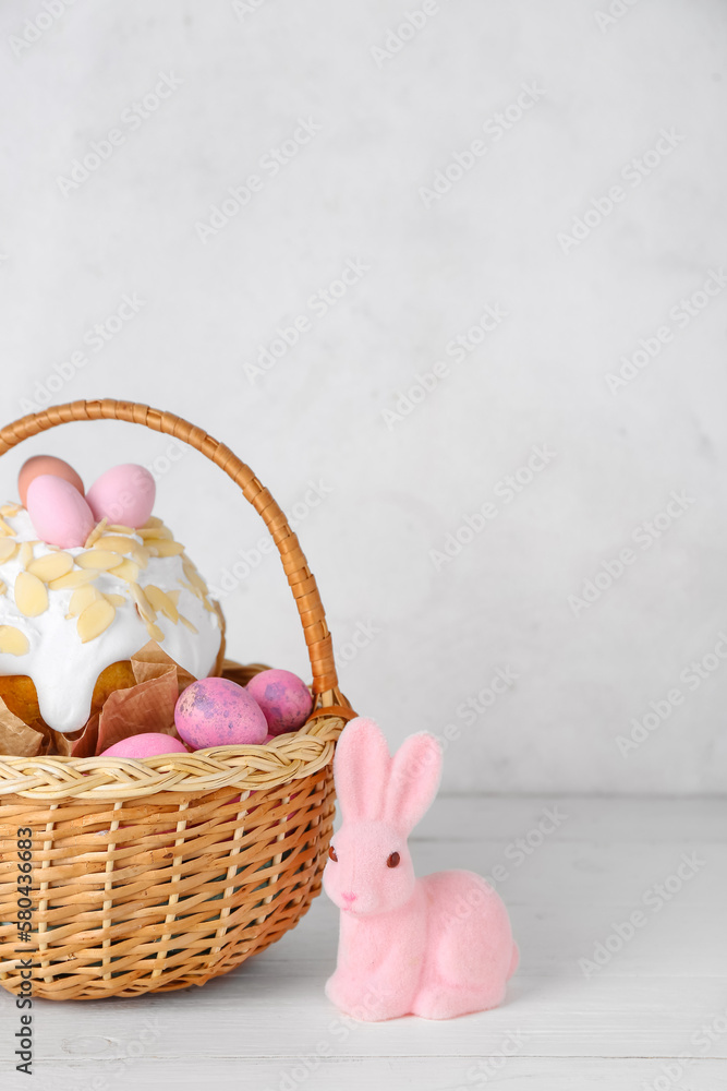 Basket with Easter eggs, cake and bunny on white background