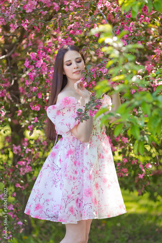  girl in a pink dress standing near pink blooming tree