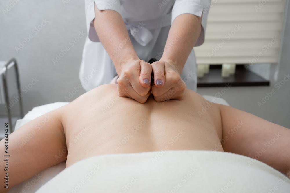 masseur doing back massage to woman masseur doing back massage to woman