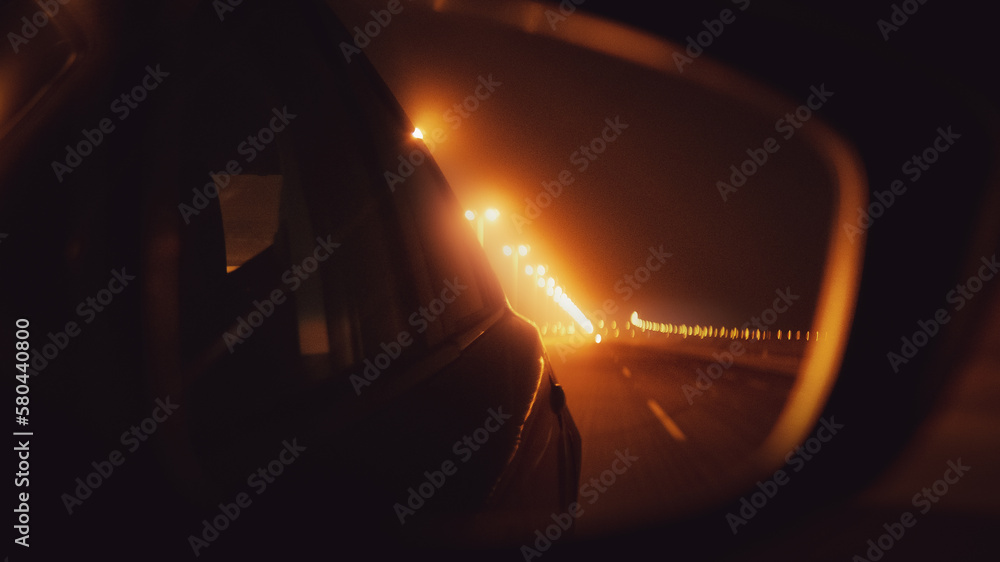Highway at night. An image from the side mirror of a car.