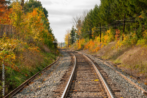 A train track bending around a corner through a forest during autumn
