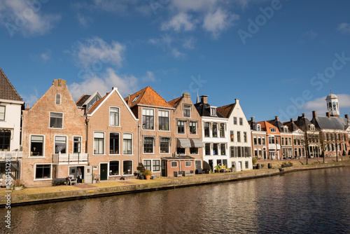 waterside residential houses on the edge of the river kleindiep waterway in Dokkum, Friesland, Netherlands Holland. old town hall in town centre with bridge on pleasant sunny day