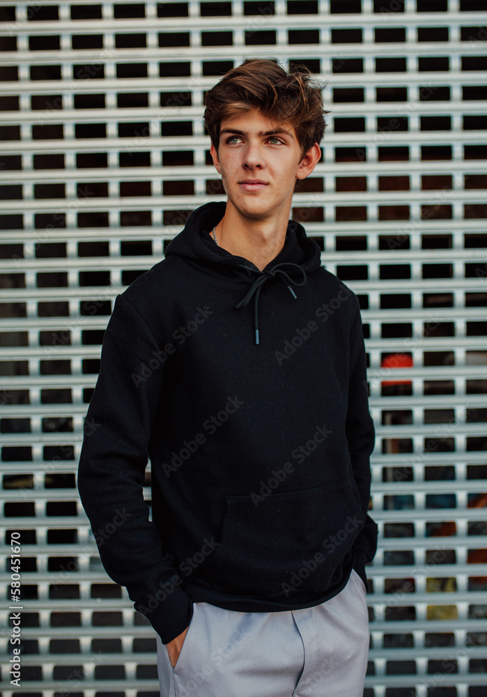 City portrait of handsome young guy wearing black blank hoodie or sweatshirt with space for your logo or design. Mockup for print City portrait of handsome young guy wearing black blank hoodie or sweatshirt with space for your logo or design. Mockup for print