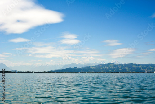 In the distance, at the foot of beautiful mountains, many yachts float. Bright turquoise sea and sky. Natural background