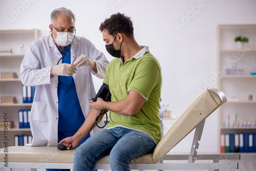 Old male doctor measuring young patient's blood pressure © Elnur