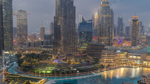 Skyscrapers rising above Dubai downtown day to night timelapse surrounded by modern buildings aerial top view