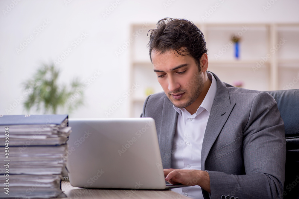 Young male employee and too much work in the office Young male employee and too much work in the office