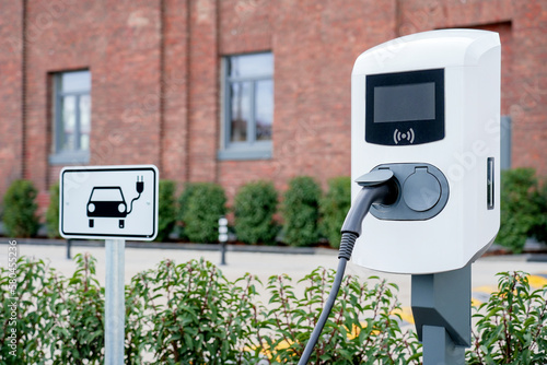 e-car charging station, e-car charge point or electric vehicle supply equipment (EVSE) with information sign electric car public charging point station and charge cable, charging plug parking spaces