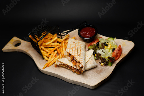 Chicken Wrap with fries isolated on black background