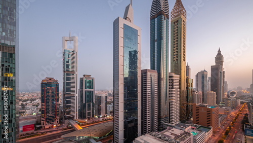 Aerial view of Dubai International Financial District with many skyscrapers night to day timelapse.