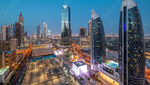 Aerial view of Dubai International Financial District with many skyscrapers day to night timelapse.