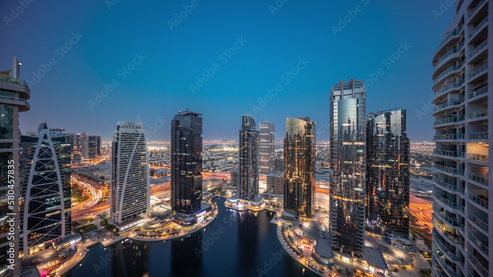 Fototapeta premium Tall residential buildings at JLT aerial day to night timelapse, part of the Dubai multi commodities centre mixed-use district.