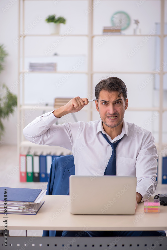 Young male employee and too much work in the office Young male employee and too much work in the office