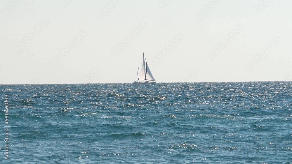 Sea travel concept, sea transport. Ocean adventure. Sailing yacht floats on waves in open sea during day. Amazing seascape on ocean horizon sailing ship. Lonely sailing ship travels on waves of sea.