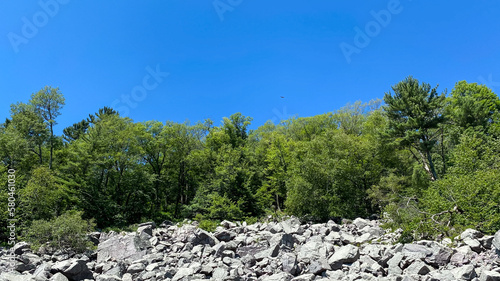 granite rocks on bluff with trees on top with blue sky
