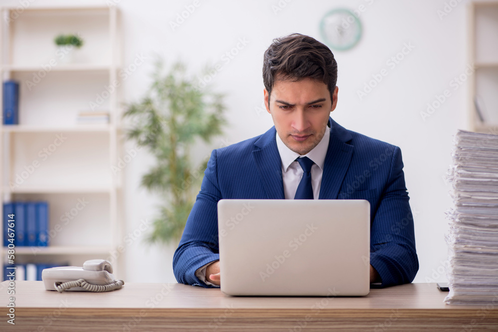 Young male employee and too much work in the office Young male employee and too much work in the office