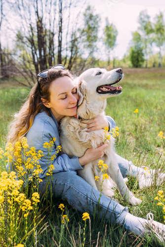 Young beautiful woman and her golden retriever dog having fun in summer