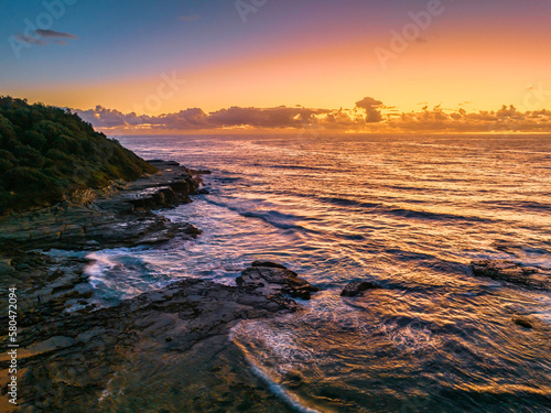 Summer sunrise at the seaside with clouds and rocks