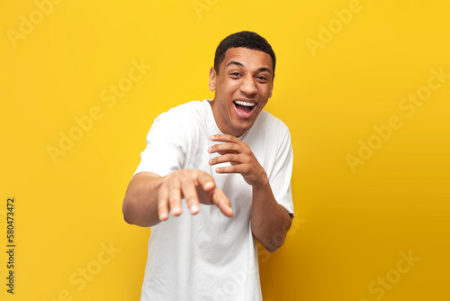 Fotografiet young funny guy african american in white t-shirt mocking and joking showing his