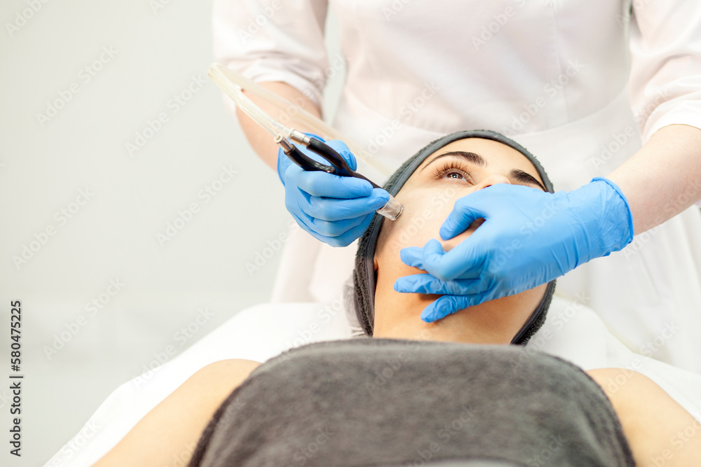 Naklejka premium procedure of vacuum cleaning of the face, doctor cosmetologist makes vacuum cleaning of the face of girl