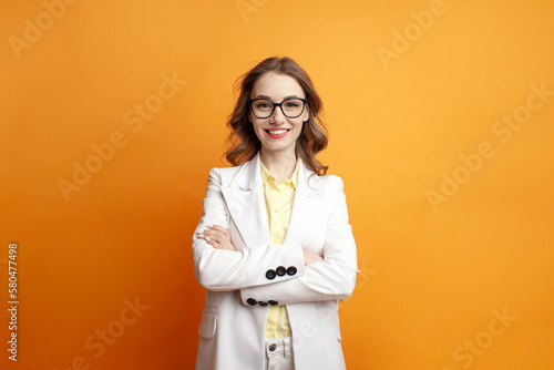 Fotomurale business woman in glasses and suit stands with her arms crossed on colored backg