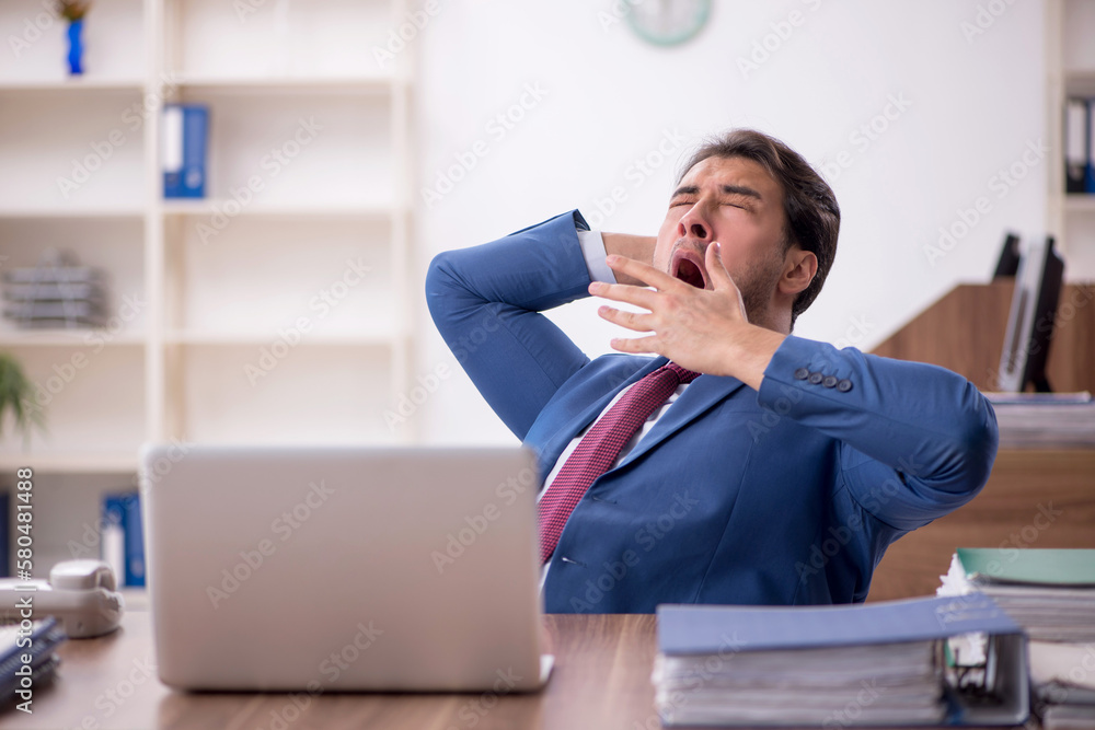 Young male employee unhappy with excessive work in the office Young male employee unhappy with excessive work in the office