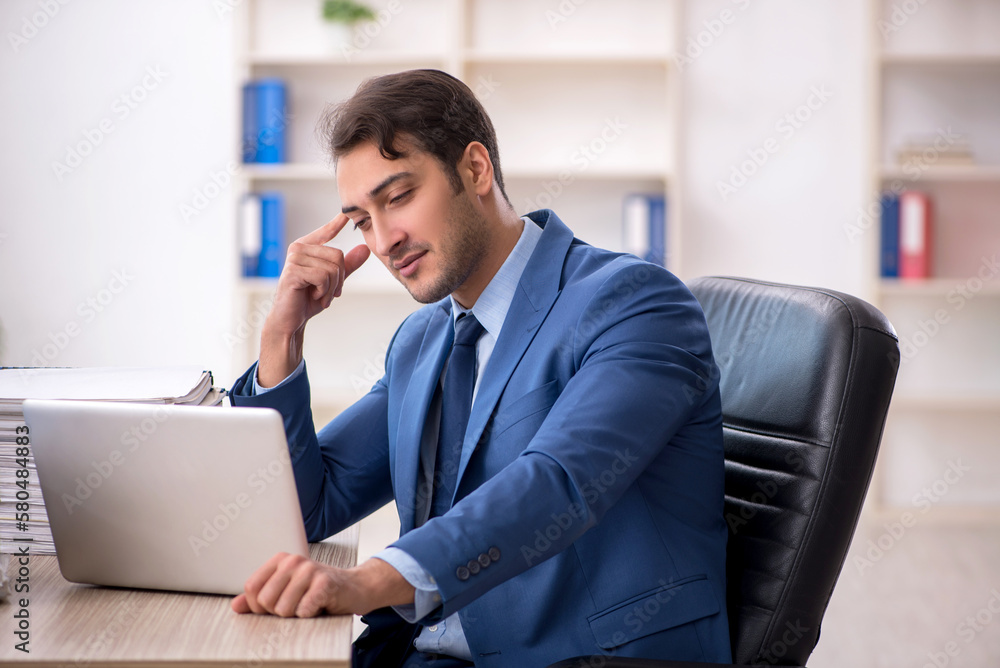 Young male employee and too much work in the office Young male employee and too much work in the office