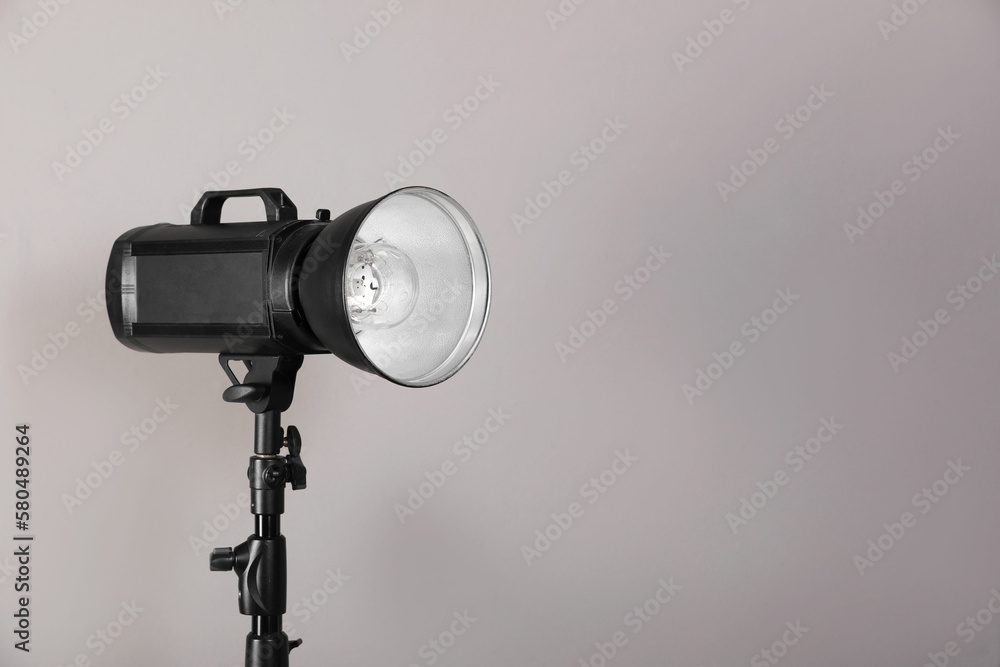 Professional studio flash light with reflector on tripod against grey background, space for text. Photography equipment Professional studio flash light with reflector on tripod against grey background, space for text. Photography equipment