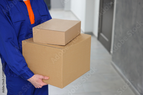 Courier with cardboard boxes in hallway, closeup © New Africa